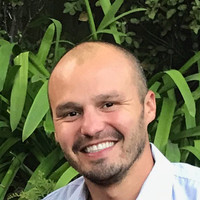 A smiling person with plants in the background.