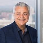 A man wearing a suit and smiling in an office setting.