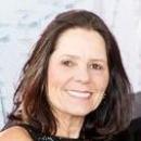 A woman smiling in front of a light background.