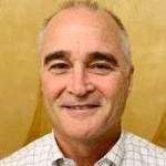 A person smiling against a yellow background.