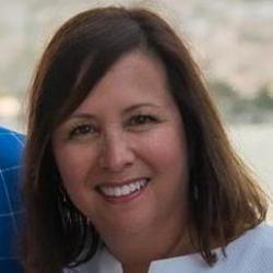 A woman smiling in front of an indistinct background.