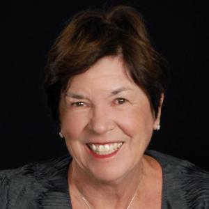 A woman smiling against a black background.
