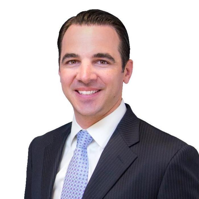 Man in a suit smiling against a white background.