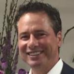 A man smiling with plants in the background.