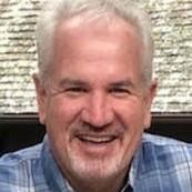 A person smiling in a plaid shirt.