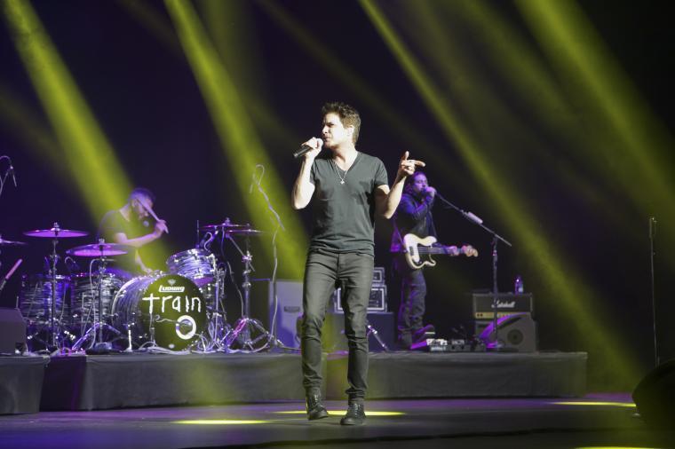 A band performing on stage with yellow spotlights.