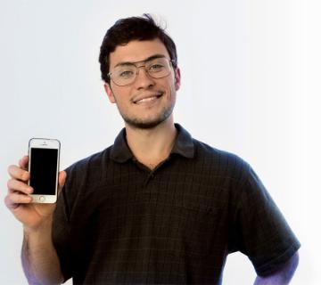 A person holding up a smartphone and smiling.
