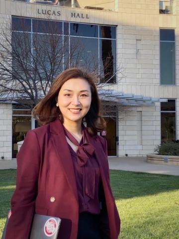 Professional picture of Jessica Yuan standing outdoors with a maroon jacket on