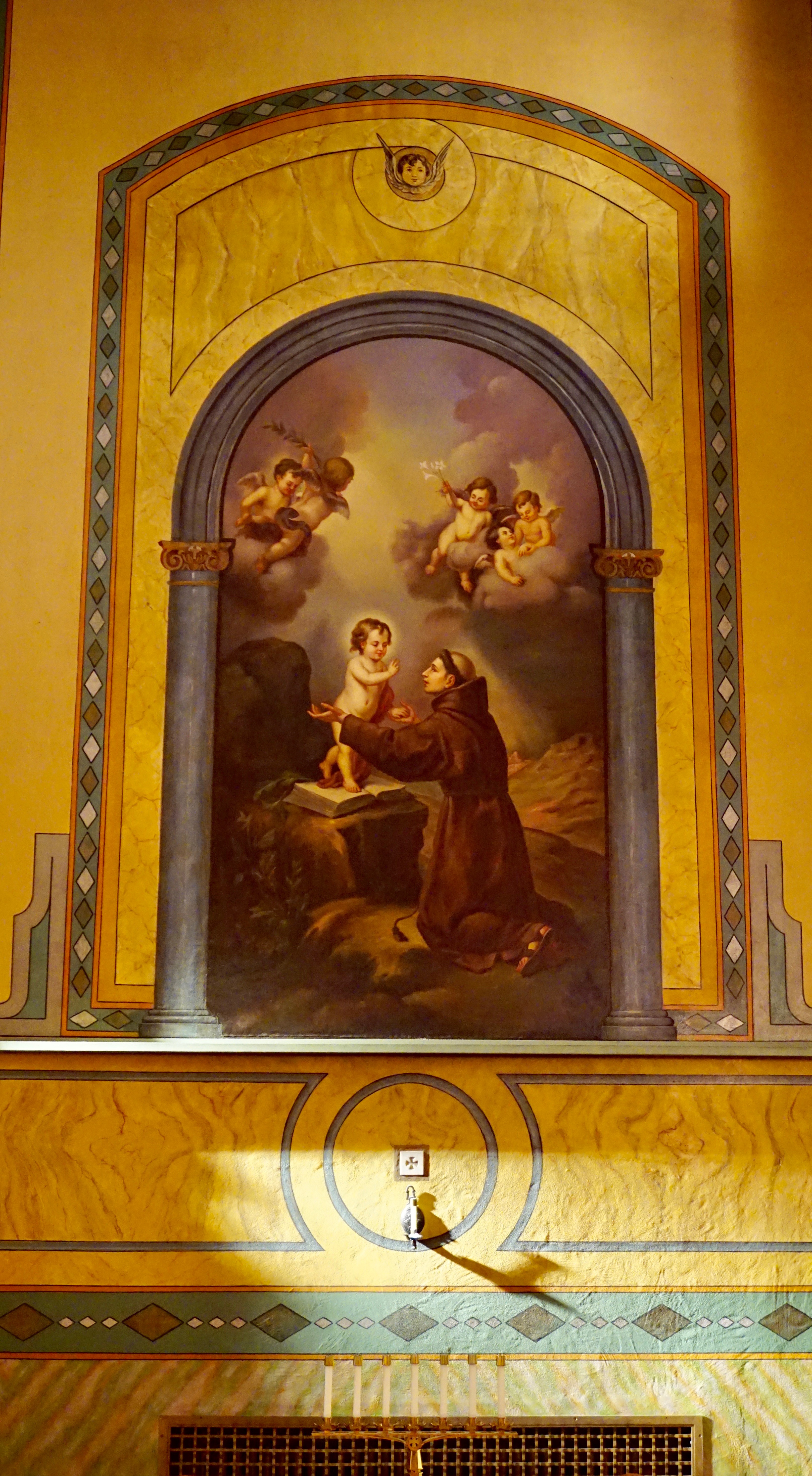 Saint Francis of Assisi statue in an arched alcove with flowers.