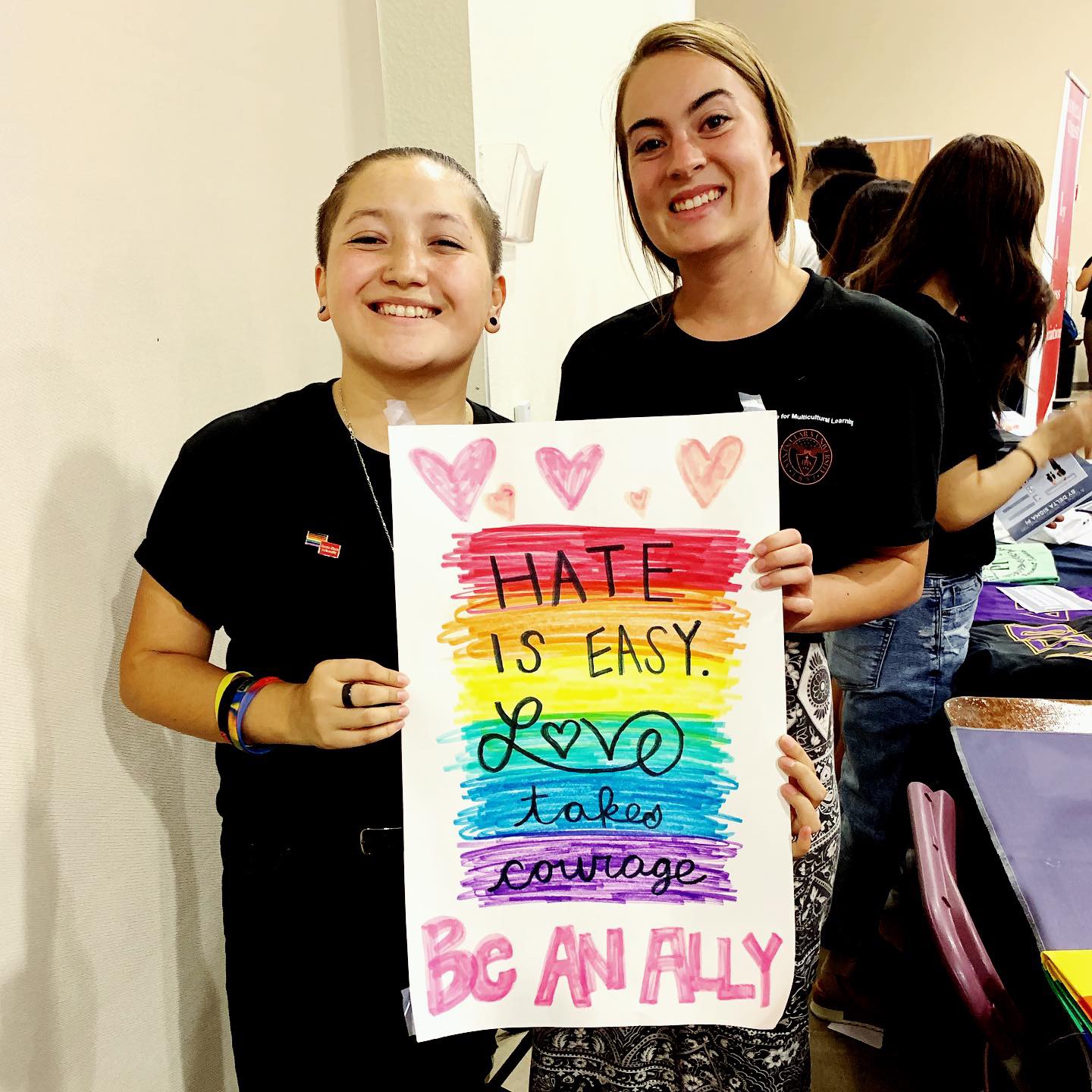 Two people holding a colorful sign with motivational text.