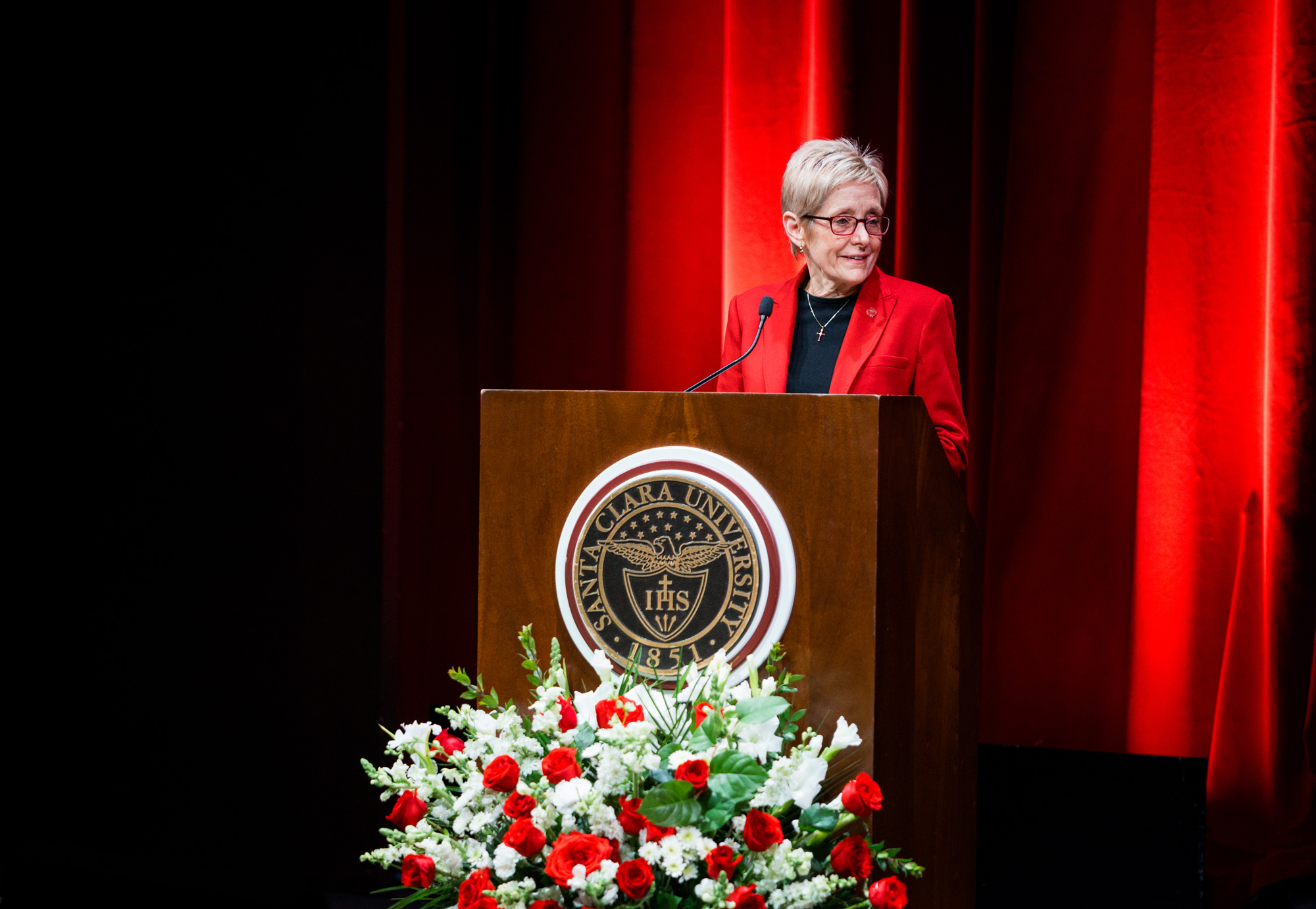 President Julie Sullivan speaking at a podium with a bouquet of roses in the foreground