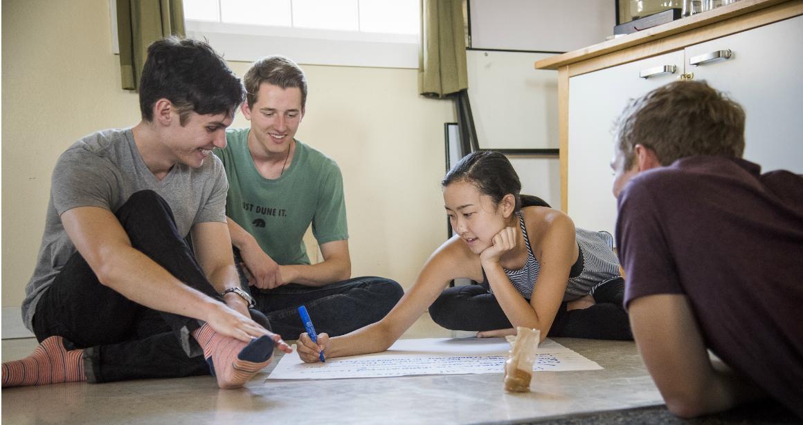 Four people collaborating on a project on the floor.