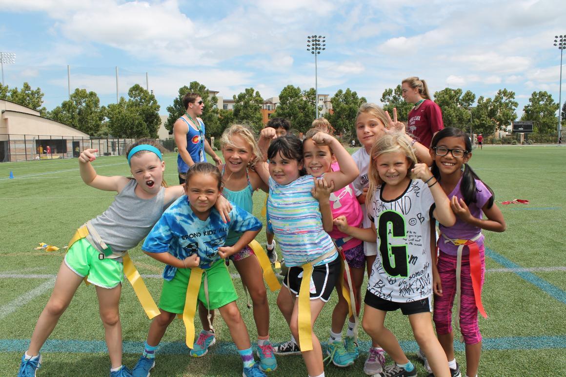A group of girls smiling on a flag football field.