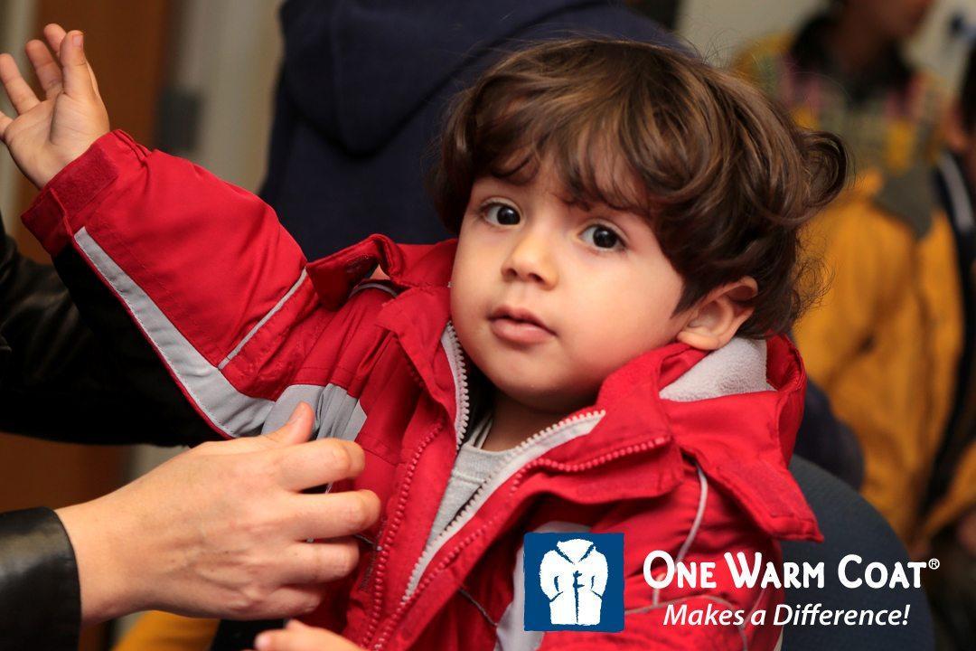 Child trying on a red winter coat with 