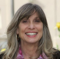 A person smiling with flowers in the background.