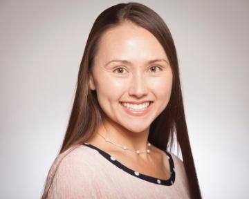 A woman smiling against a light gray background.