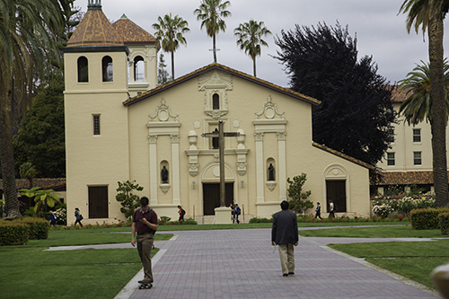 Two people walking towards a historic mission-style building. 