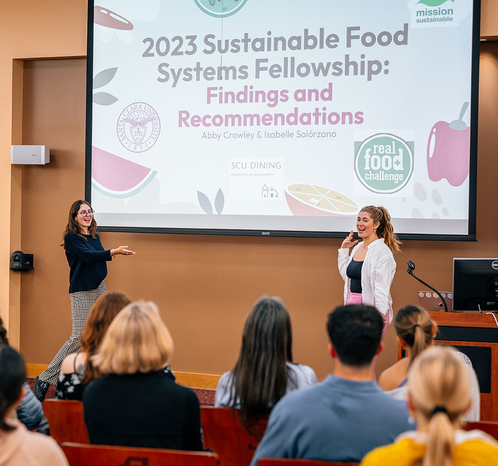 Two female students presenting in front of a screen at the Sustainability and EJ Symposium