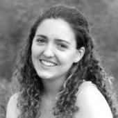 A woman smiling outdoors in black and white.