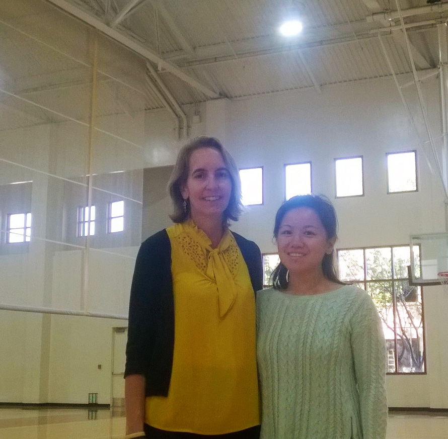 Two people in a gymnasium, standing and smiling for a photo.