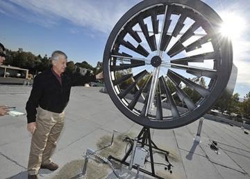 A person stands beside a portable wind turbine.