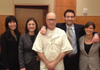 A group of five people smiling and posing for a photo.