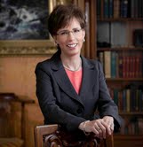 A person in formal attire in a library setting.