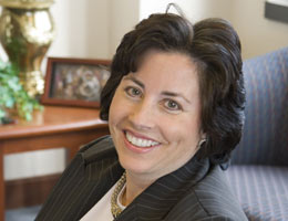 A person smiling while sitting in an office chair.