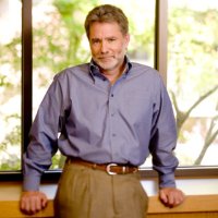 Person standing in front of windows with a scenic background. image link to story