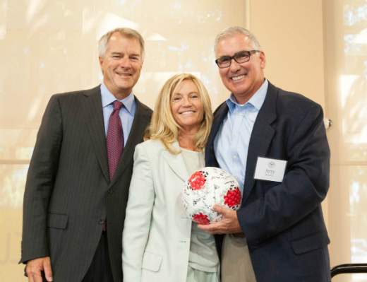 Three people posing with a small ball at an event. image link to story
