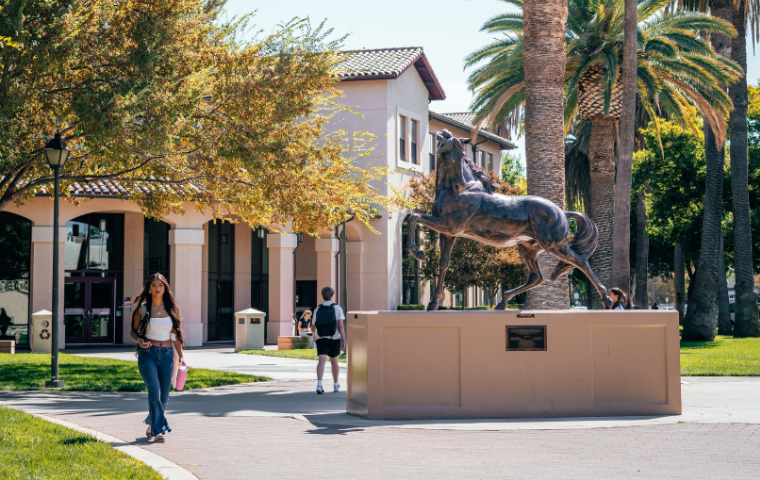 A male student and a female student walking past the large bronco statue image link to story