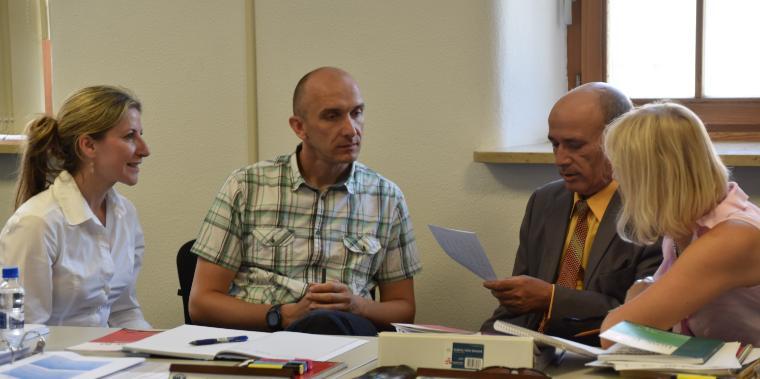 Four people having a discussion around a table with documents.