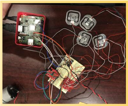Arduino with black, red, and while wires leading to load cells for testing the readings during prototyping on a brown table.