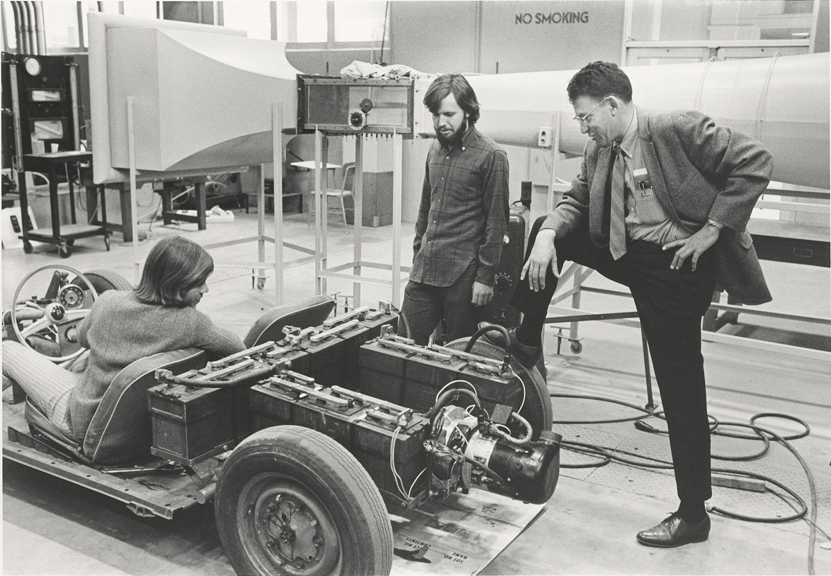 Richard (Dick) Pefley with students working on a vehicle in a workshop.