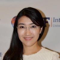 A person smiling in front of a step-and-repeat banner.