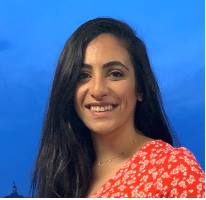 A person smiling against a blue sky background.