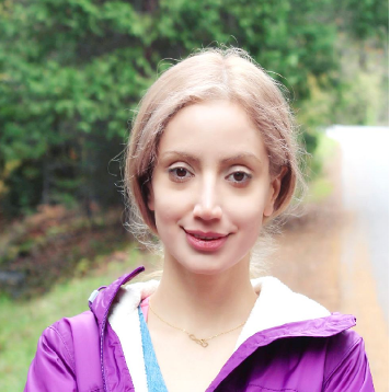 A person in a purple jacket standing outdoors.