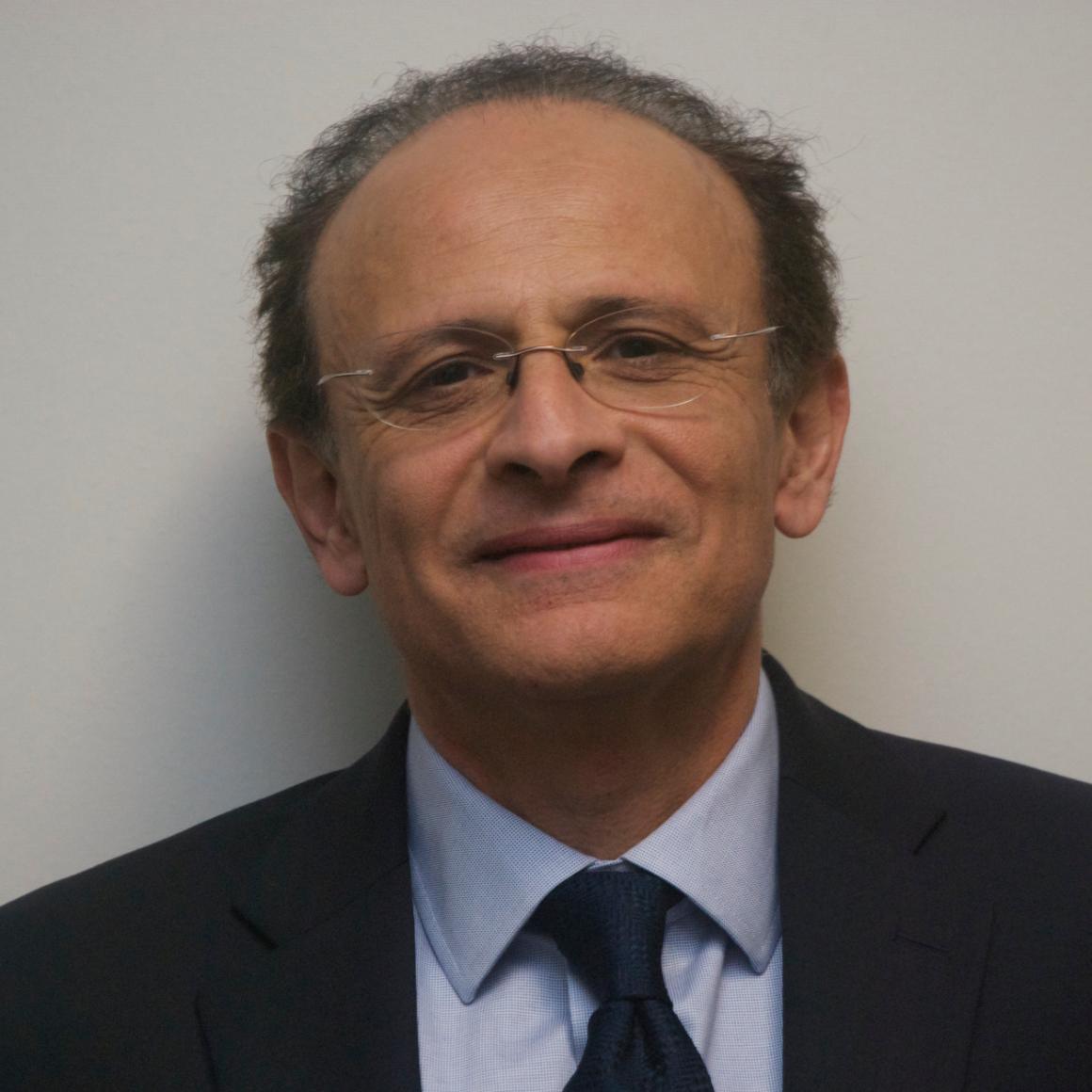 A man wearing glasses, a suit, and a tie.