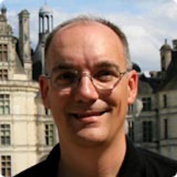 A person smiling with buildings in the background.