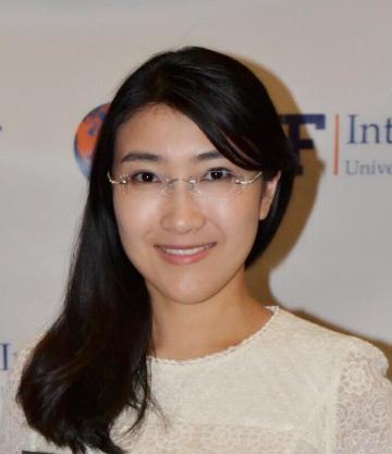 A person smiling against a branded backdrop.