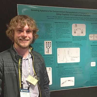 Atticus McCoy standing with his research poster at Pittcon
