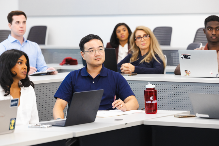 Graduate students in class with laptops and a red water bottle that reads SCU