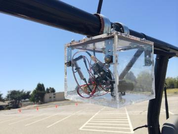An acrylic box created using a laser cutter houses camera and electronics is mounted on an autonomous vehicle