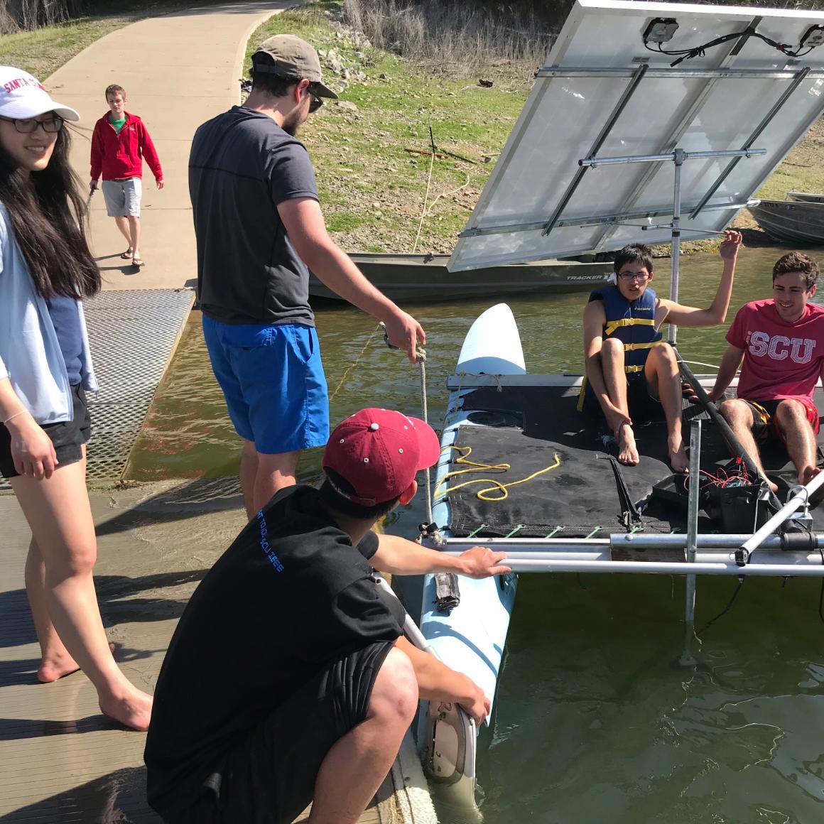 Students prep their solar-powered catamaran for launch.