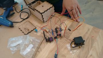 Person working on an Arduino project with electronic components and tools on a table.