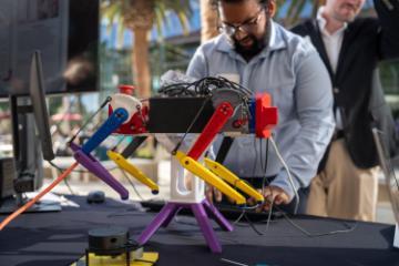 A 3D printed robotic dog being demonstrated at the 2024 Senior Design Conference by an engineering student. 