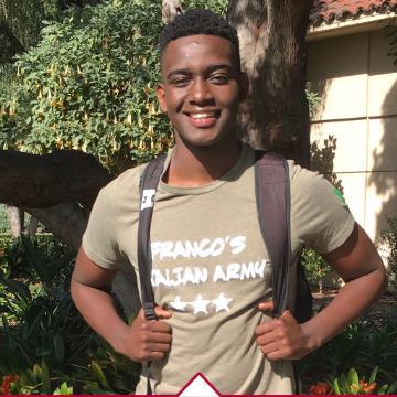 A person wearing a t-shirt with a backpack, outdoor setting.