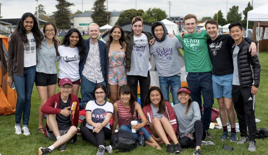 A group of people outdoors posing together, some standing, some crouching.