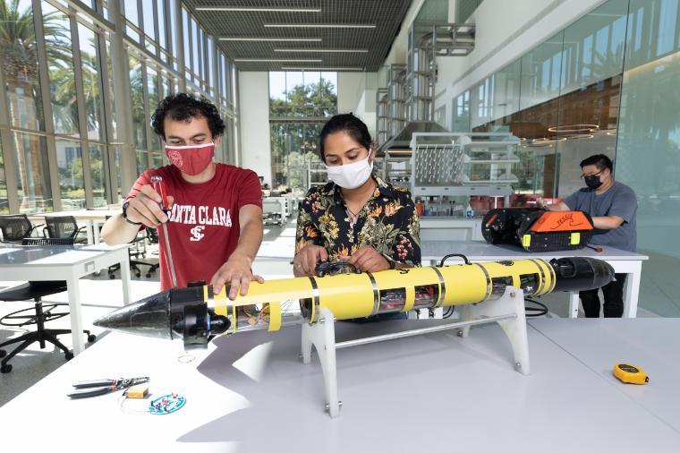 Two students working on a yellow robot