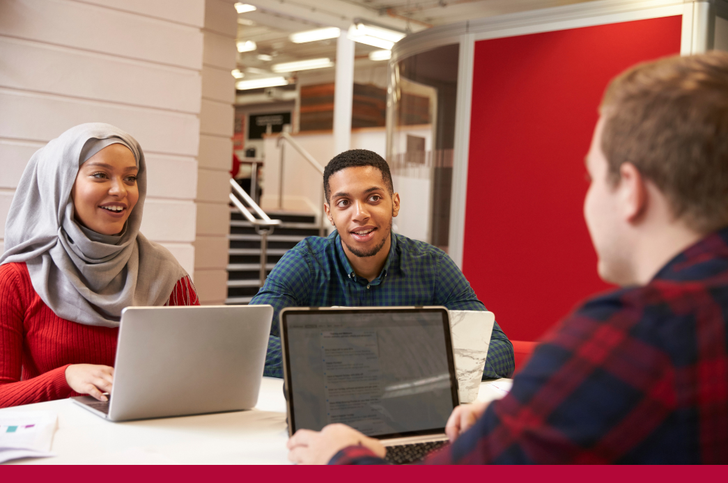 Three students collaborate on laptops 